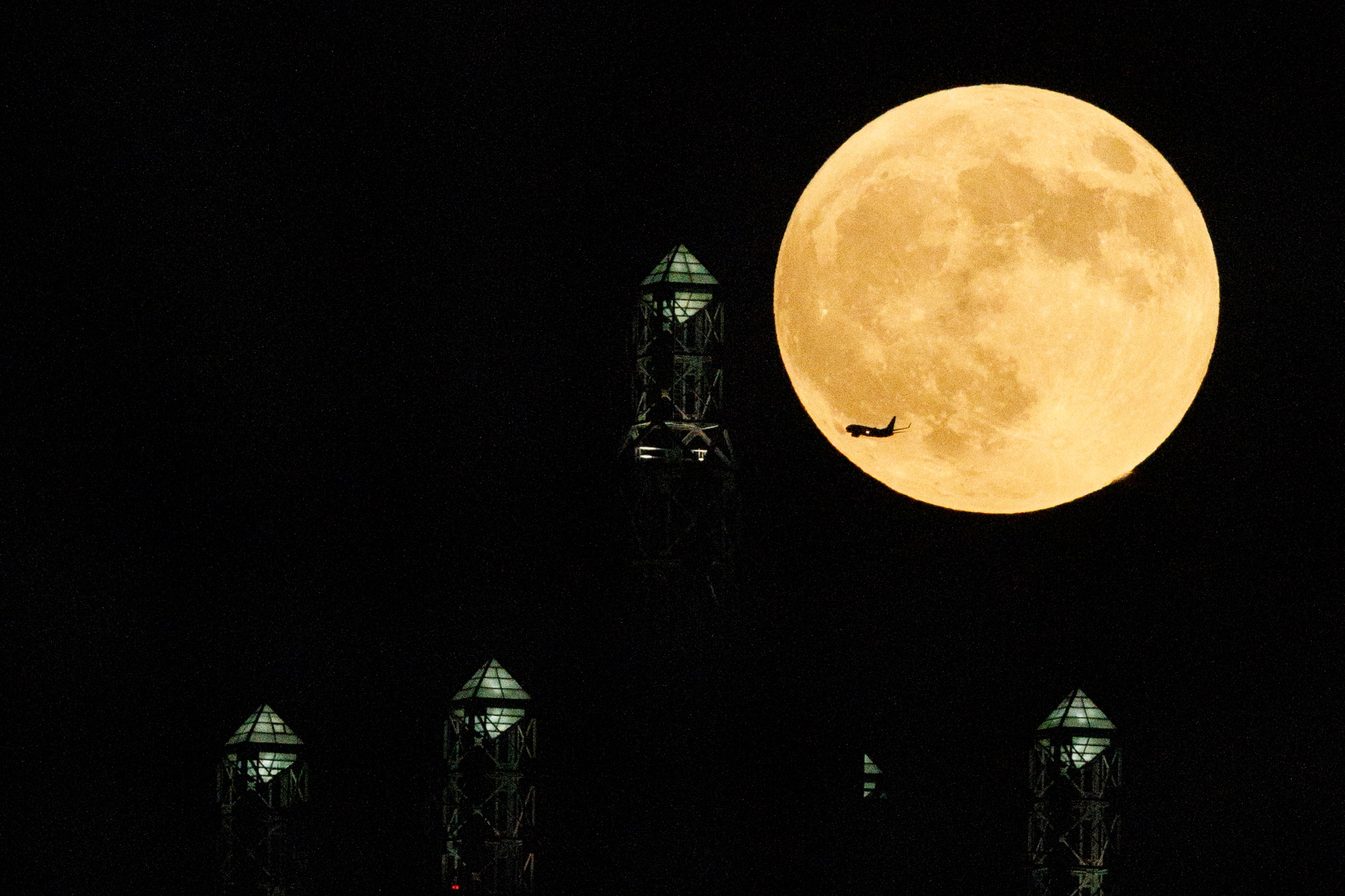 A plane flies past a partial lunar eclipse and supermoon over Renaissance Tower in downtown...