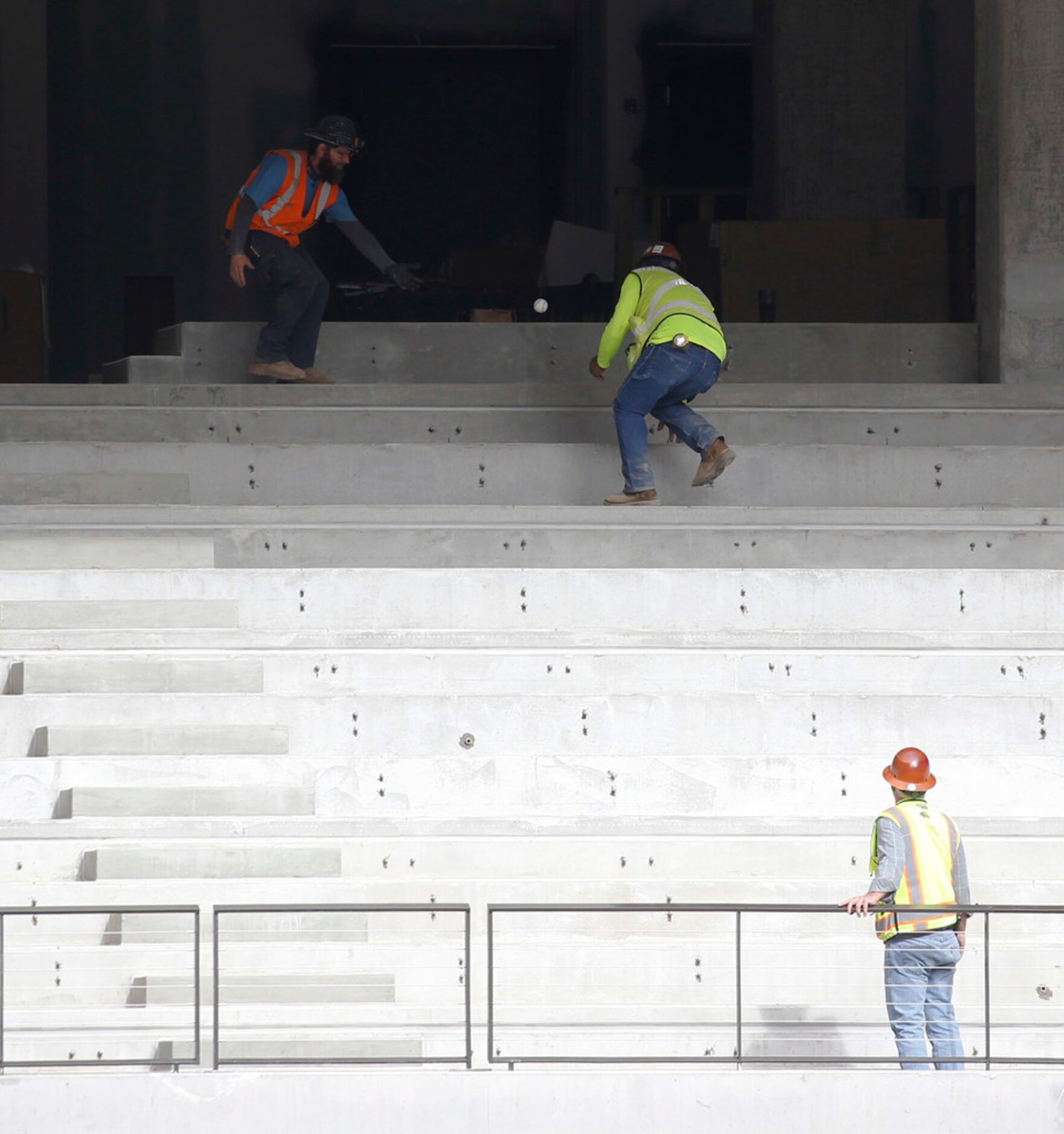 Construction crew chase after a home run baseball after as Texas Rangers players hit the...