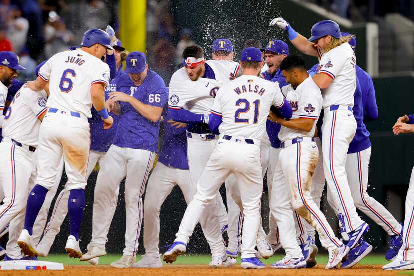 Jonah Heim, center, of the Texas Rangers, is congratulated by his team for hitting the...