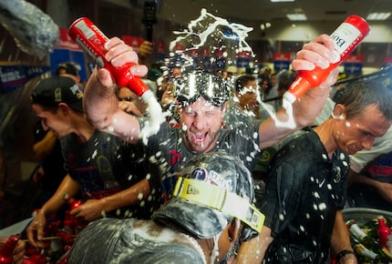 Texas Rangers pitcher Max Scherzer douses right fielder Adolis Garcia as Rangers players...