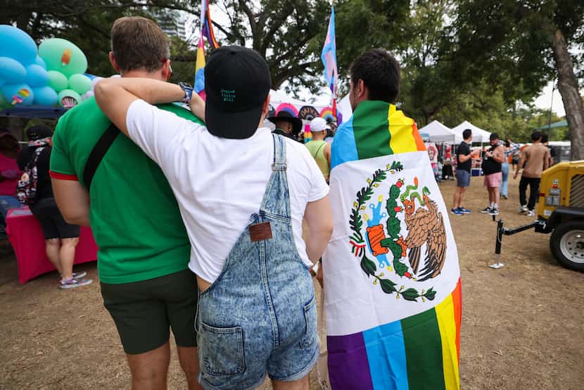 A festival-goer is wrapped in a Latinx Pride flag as the group looks at a booth at the Texas...