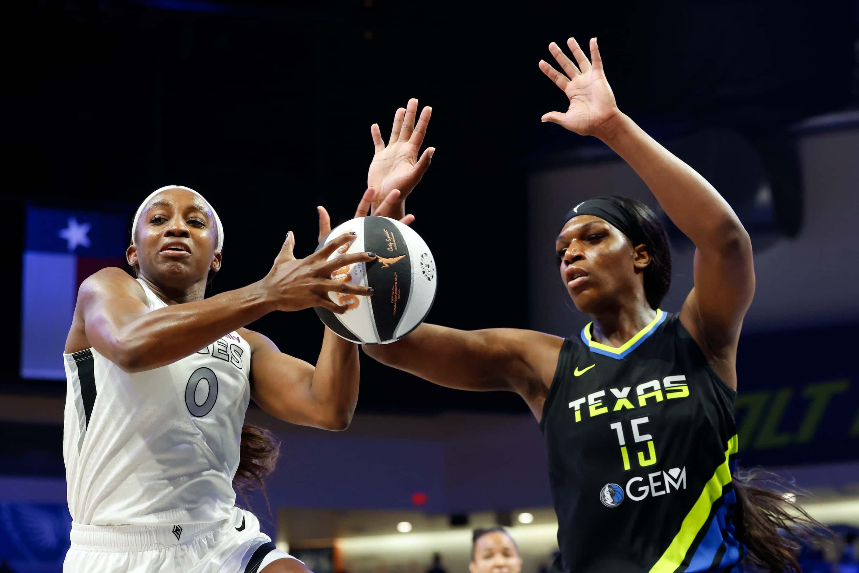 Las Vegas Aces guard Jackie Young (left) takes control of the ball past Dallas Wings center...