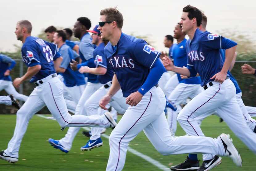 Texas Rangers pitchers and catchers, including pitcher Kyle Bird (center), run on a...