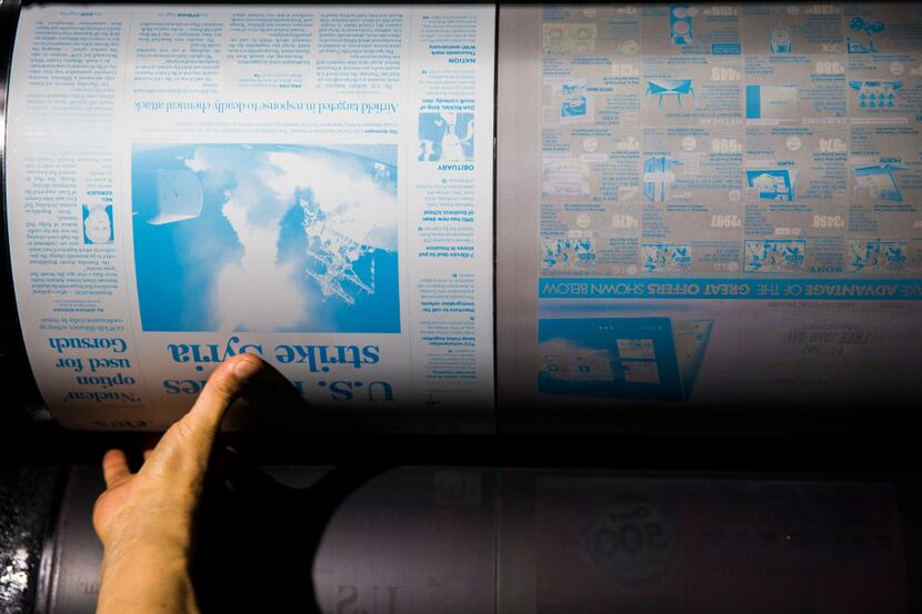 Victor Vega places a plate of the front page of The Dallas Morning News on a printing press...