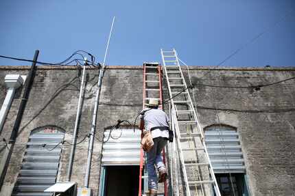 John Paul Frederick, co-owner of the Estelle Stair Gallery, climbs to the roof to help with...