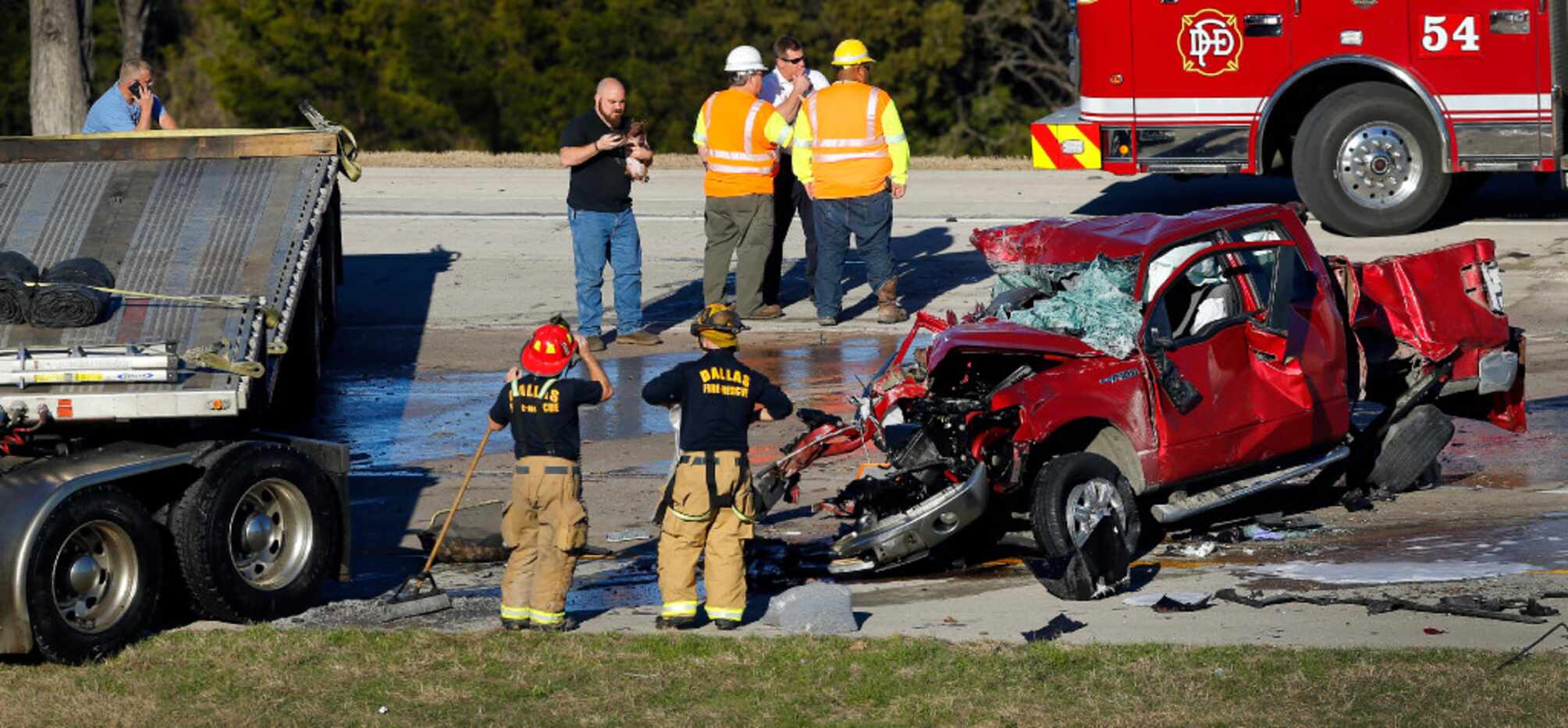 Dallas firefighters clean up after two tractor-trailers and a pickup were involved in a...