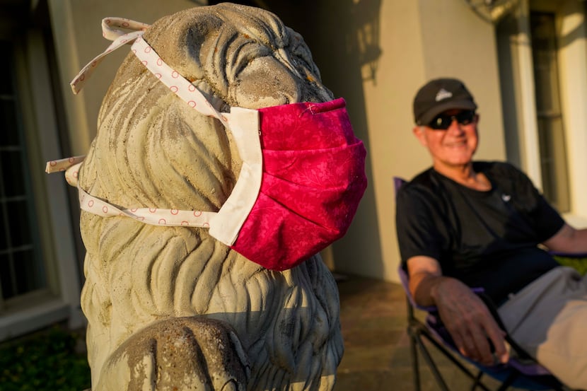 Beside a masked lion statue, Kirk Lipscomb watches from their driveway as Cameron Havens...