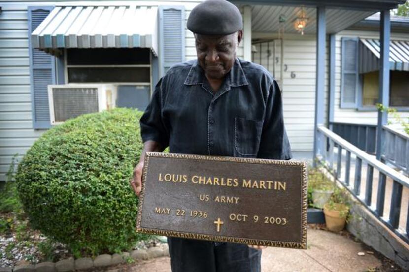 
Louis Kenneybrew III of Oak Cliff holds the grave marker of U.S. Army veteran Louis Charles...