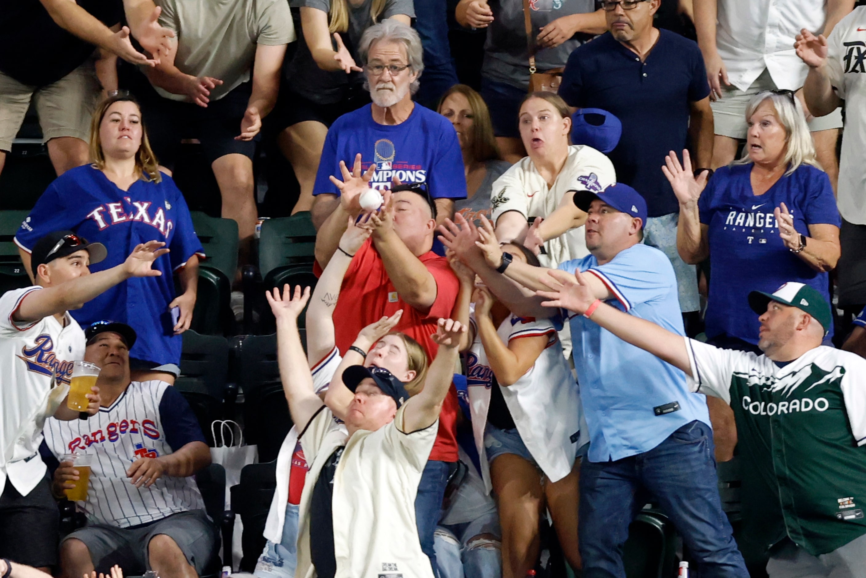 Baseball fans reach to catch a ball thrown by Seattle Mariners center fielder Julio...