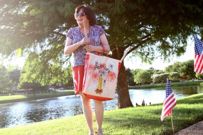 Dressed in red, white and blue, Nell Anne Hunt, carries flags during a flag distribution of...