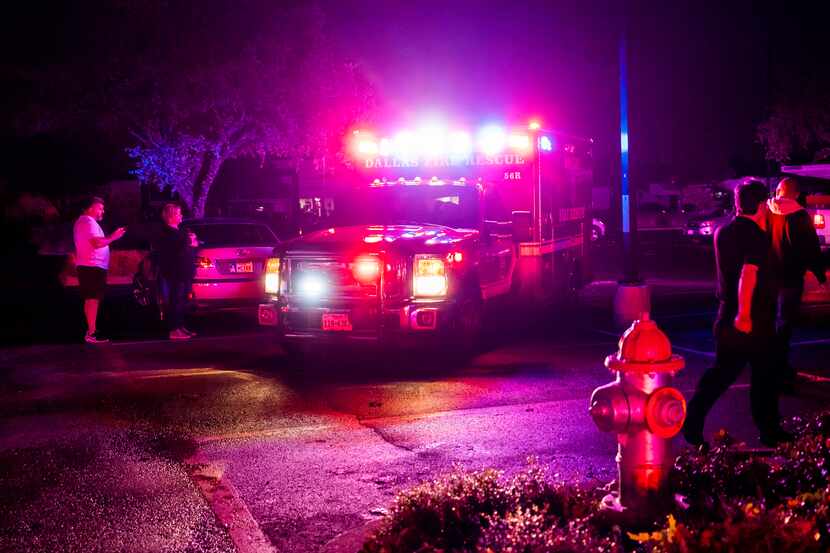 A Dallas Fire-Rescue ambulance moves through a shopping center parking lot after a tornado...