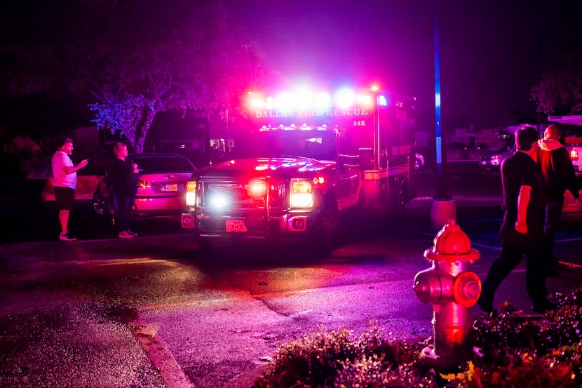 A Dallas Fire-Rescue ambulance moves through a shopping center parking lot after a tornado...