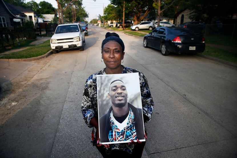 Rena Hightower poses with a portrait of her nephew Michael Tilley in front of her house in...