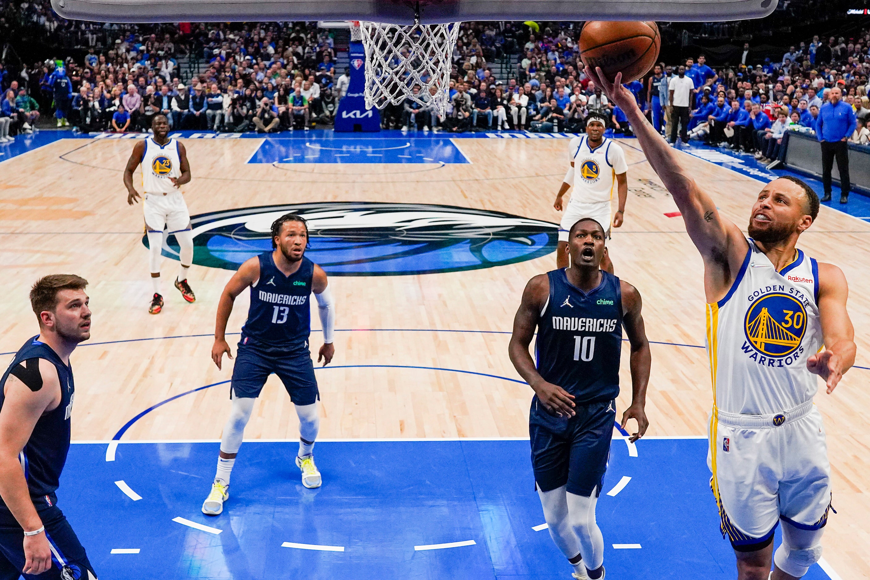 Golden State Warriors guard Stephen Curry (30) scores past Dallas Mavericks guard Luka...