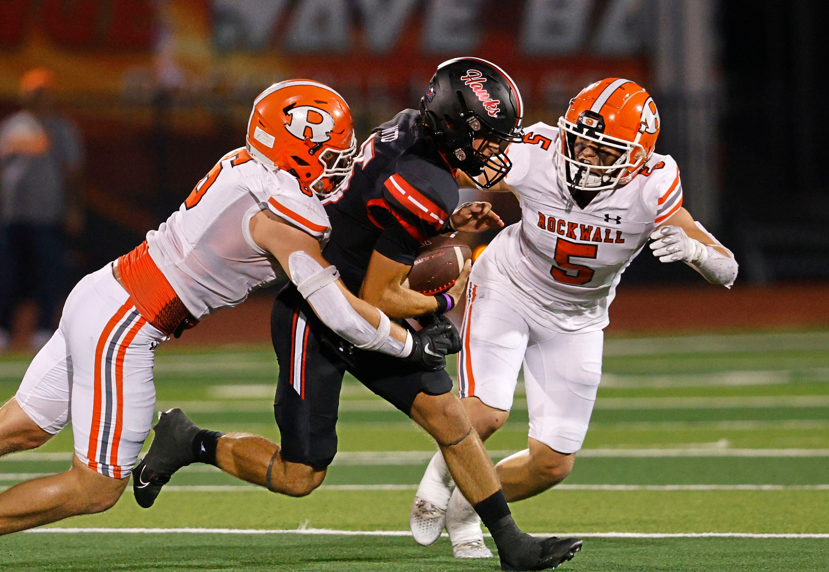 Rockwall-Heath's quarterback Landon Dutka (15) is tackled by Rockwall's Hayden Curry (6) and...