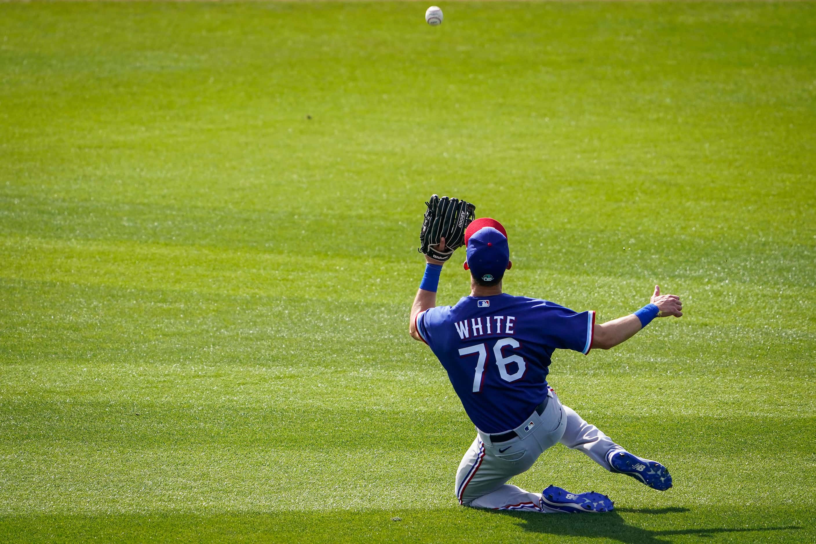 Texas Rangers center fielder Eli White makes a sliding catch on a line drive by Kansas City...