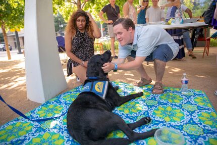 Michael Poston (right) pets Yoshi, as Brielle Robertson looks on at Klyde Warren Park in...