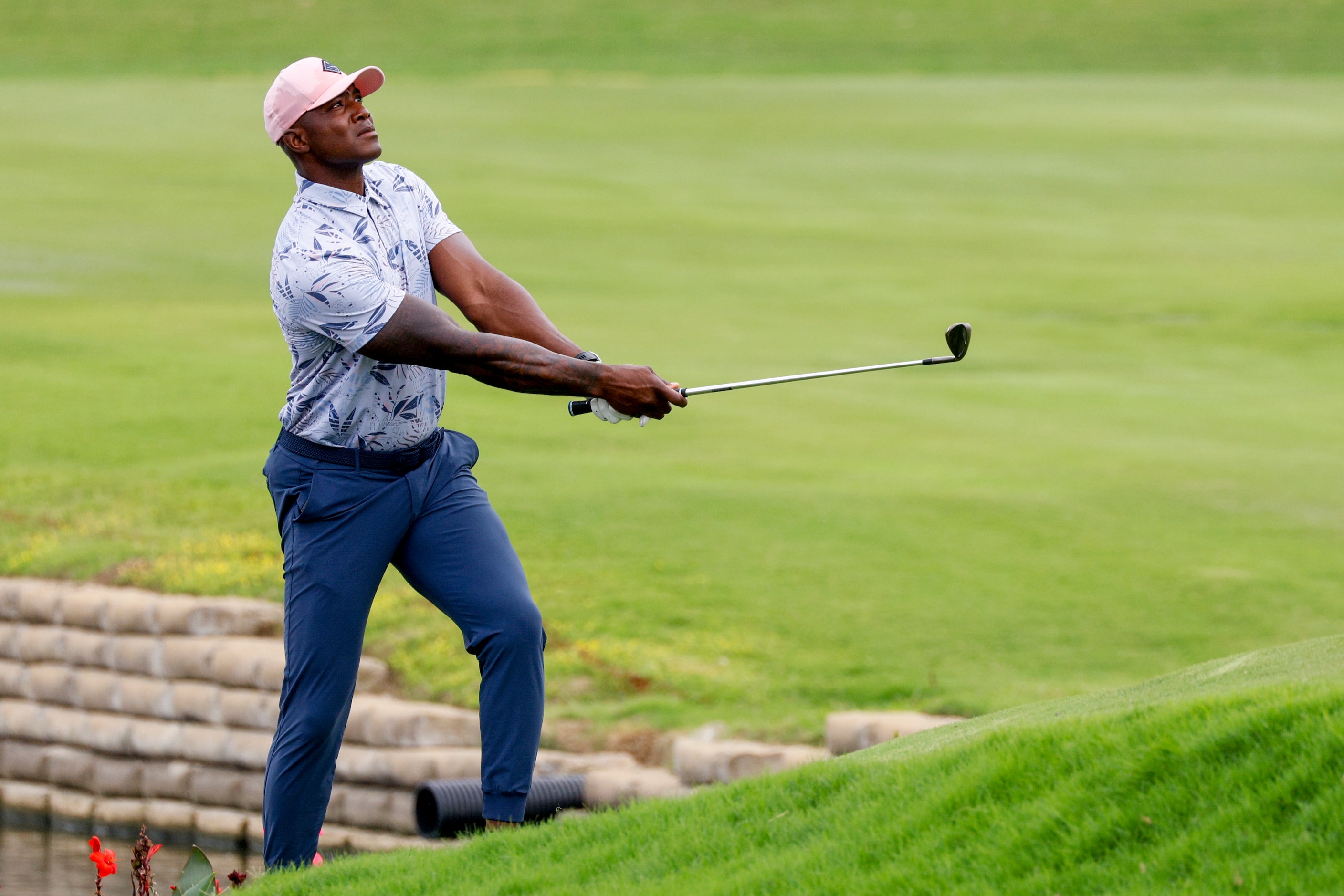 Former Dallas Cowboys player DeMarcus Ware chips onto the 15th green during the first round...