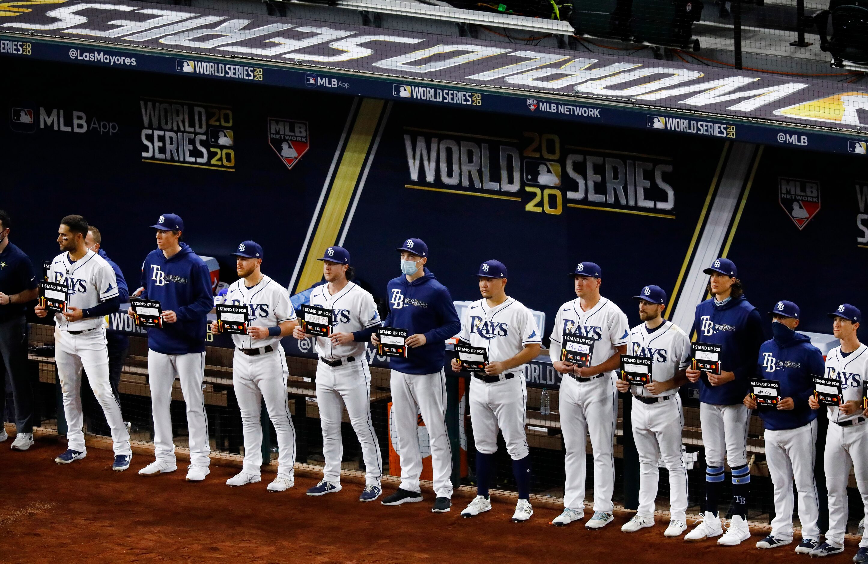 The Tampa Bay Rays baseball team line the dugout with their Stand Up For Cancer signs during...