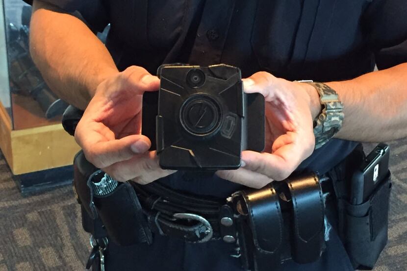 A Dallas police officer holds a Taser Axon Flex body camera that the department began using...