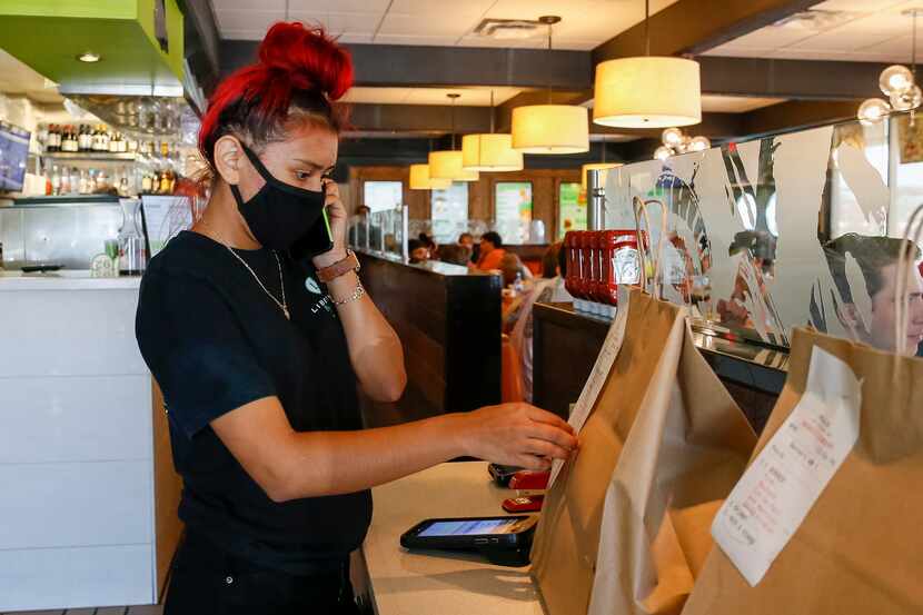 Liberty Burger employee Nicole Romero checks a to-go order while answering the phone at...