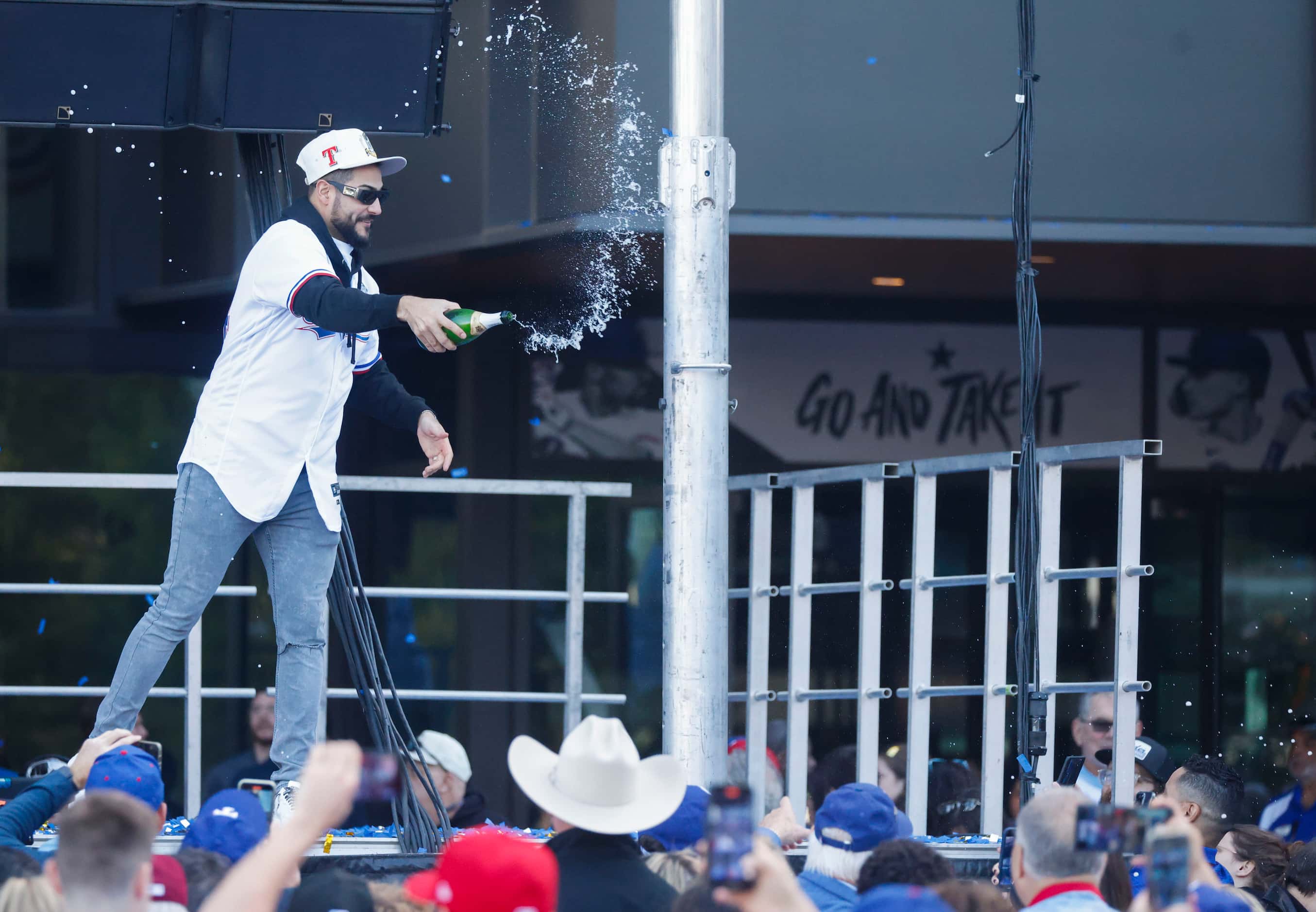 Texas Rangers pitcher Martín Pérez sprays champagne towards the crowd after post-parade...