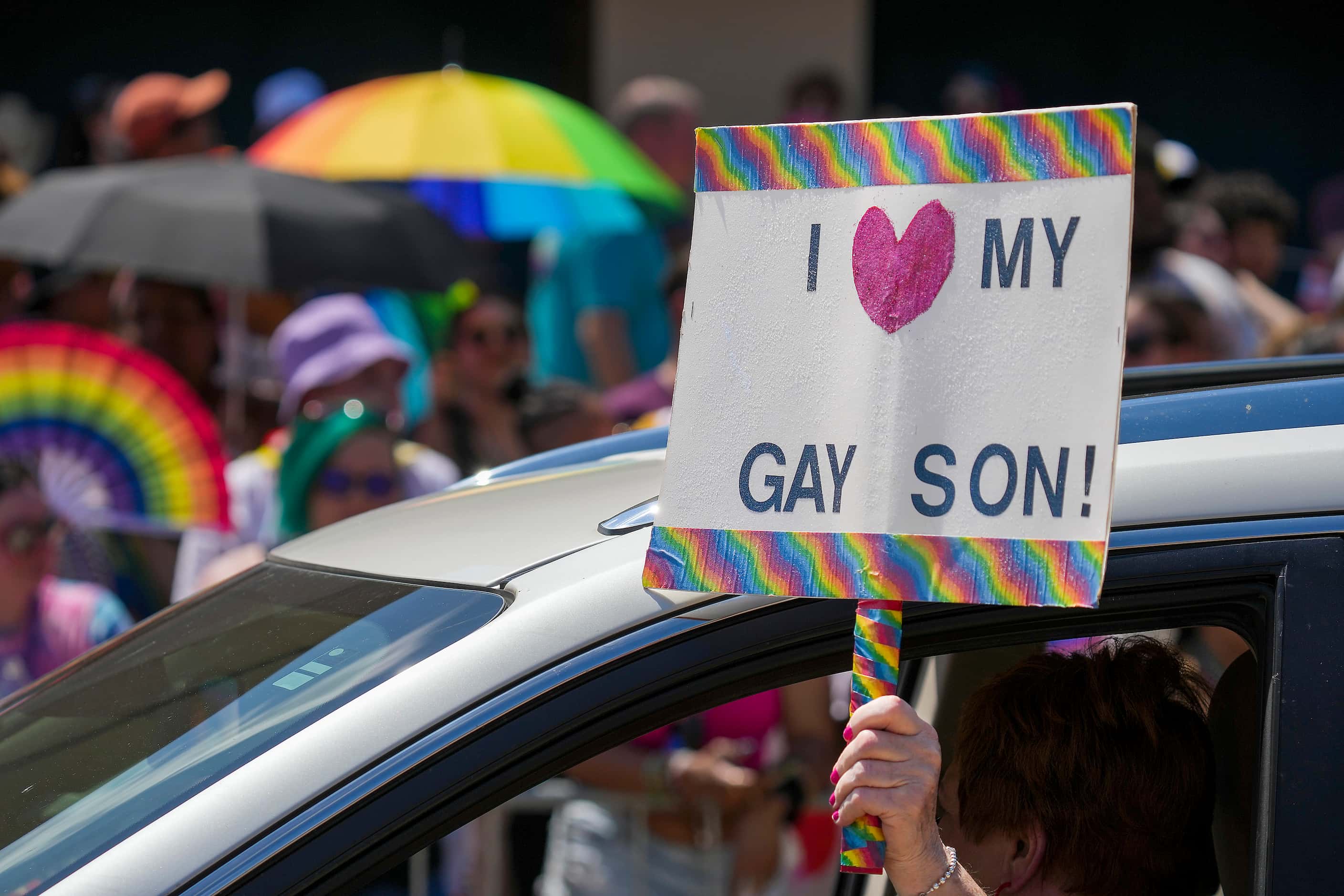 A participant representing PFLAG holds a sign from a car  during the annual Alan Ross Texas...
