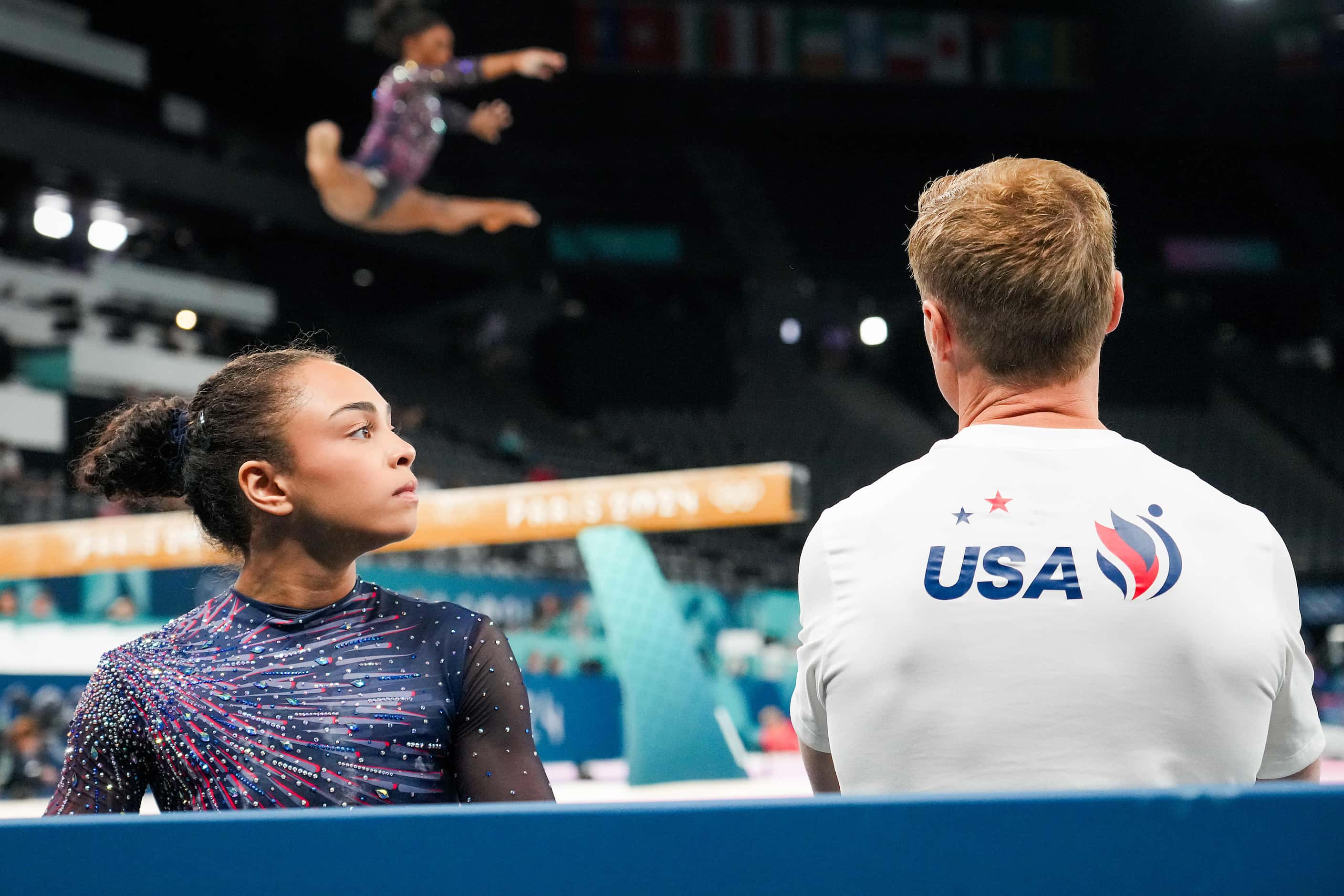 Hezly Rivera of the United States talks with coach Valeri Liukin as Simone Biles practices...