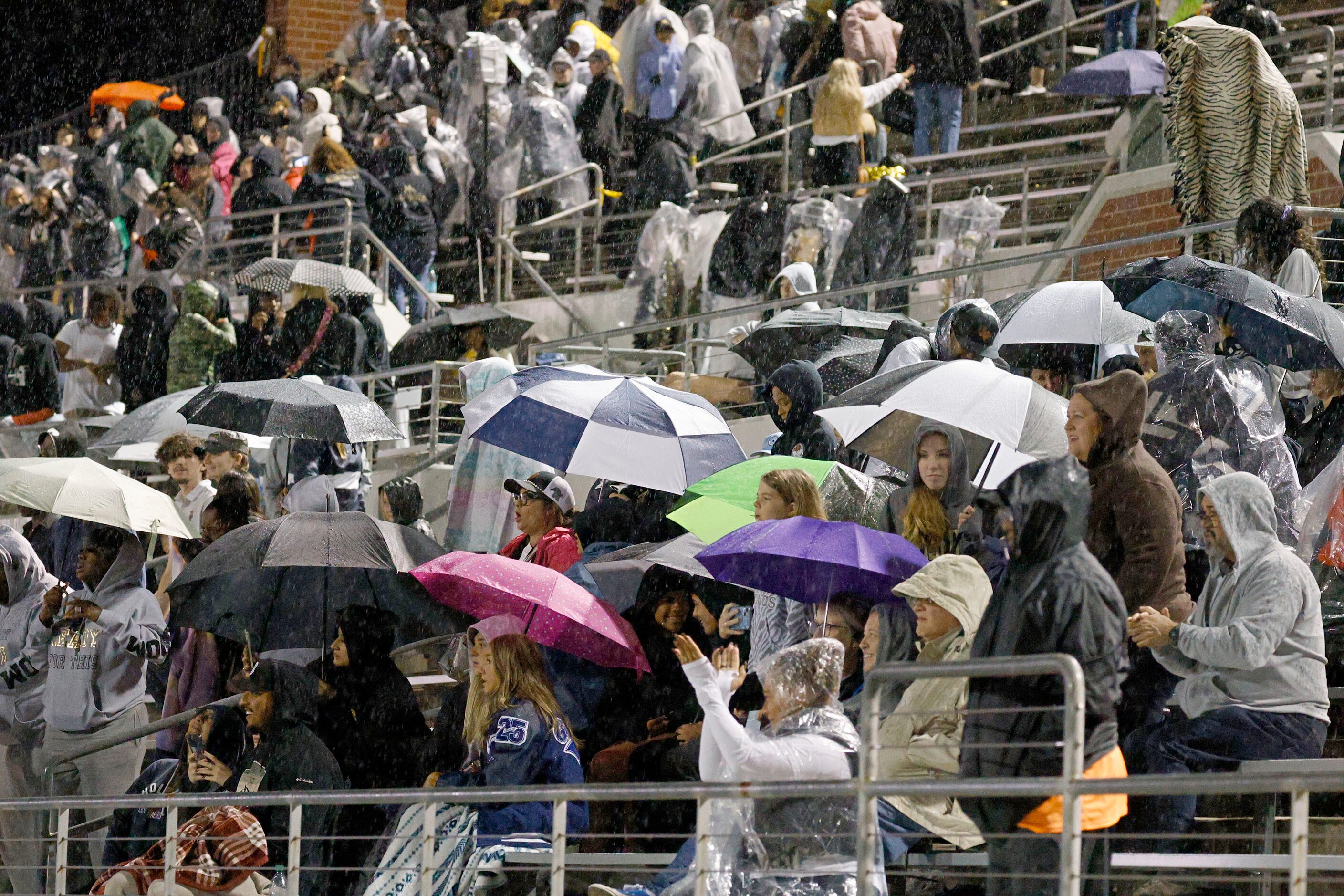 People watch a high school football game between Mansfield  and Weatherford in the rain at...