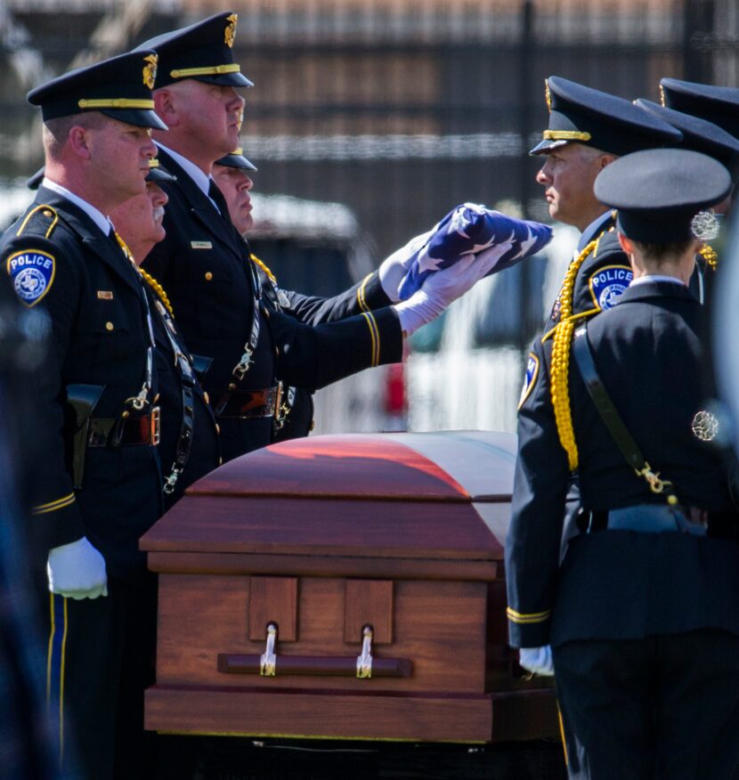  Officers fold an American flag over a casket containing the remains of Euless police...