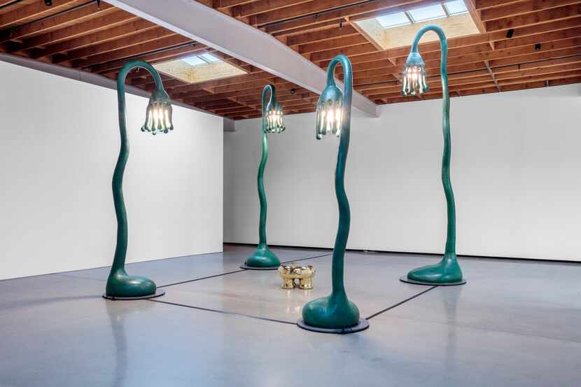 Sculpture installation featuring four large stylized street lamps around a stool.