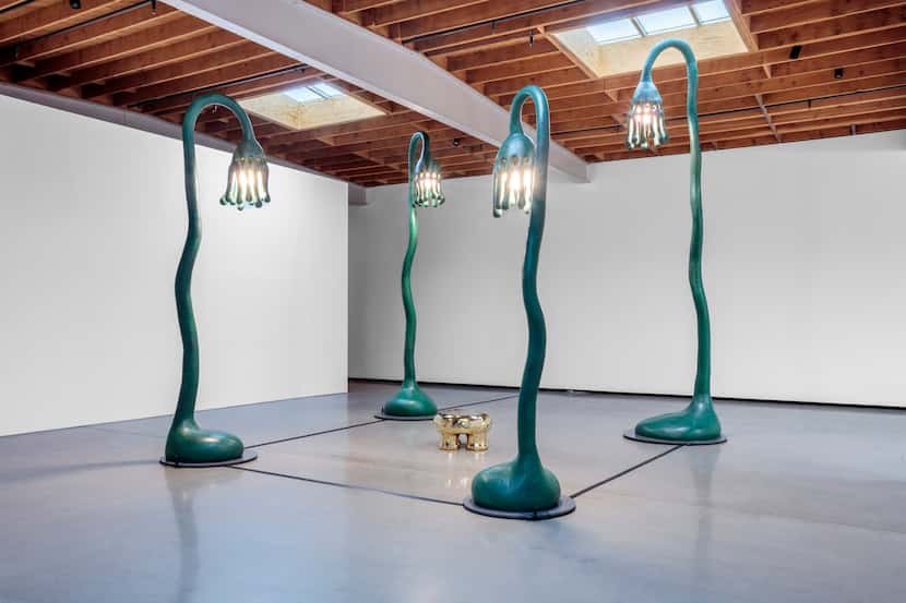 Sculpture installation featuring four large stylized street lamps around a stool.