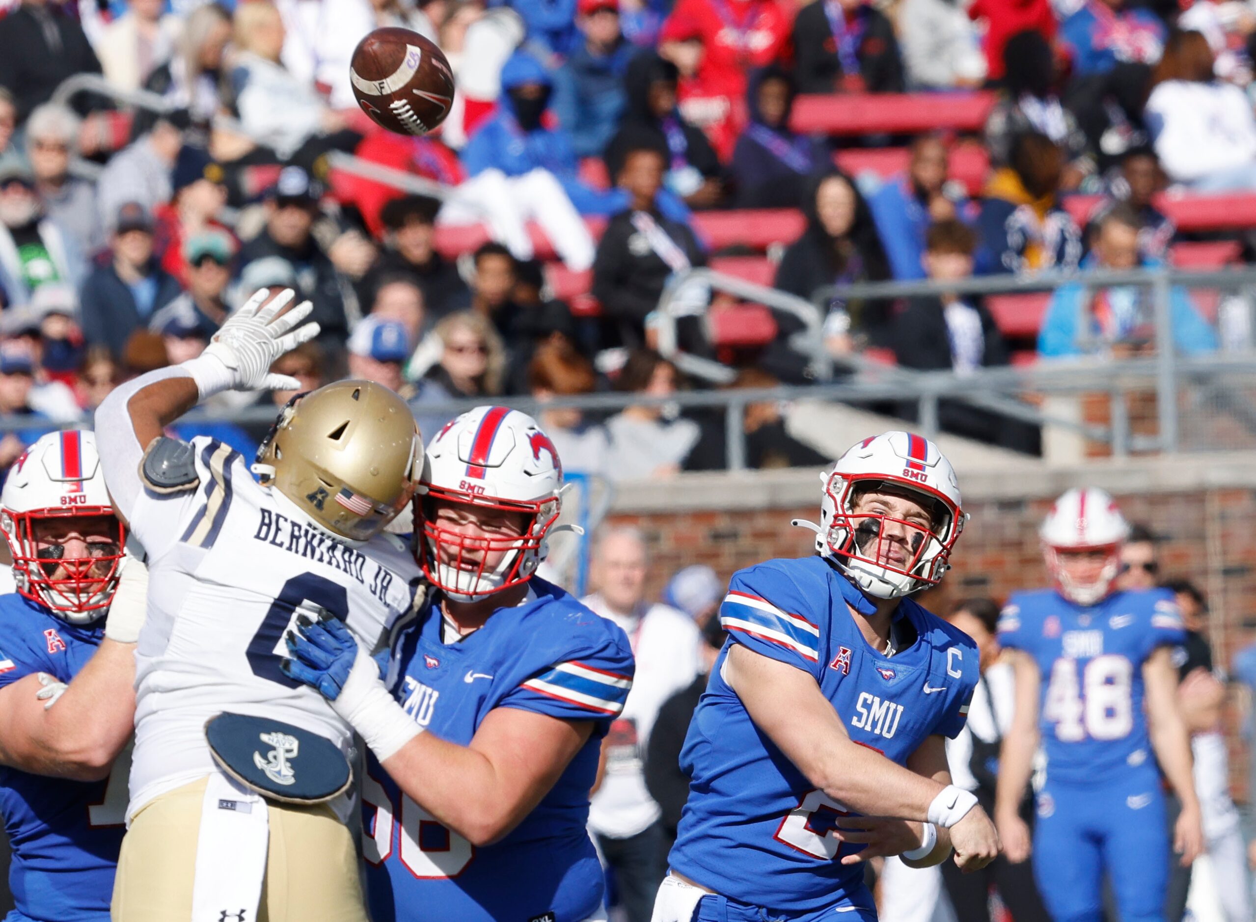 SMU quarterback Preston Stone, left, passes under pressure from Navy guard Donald Berniard...