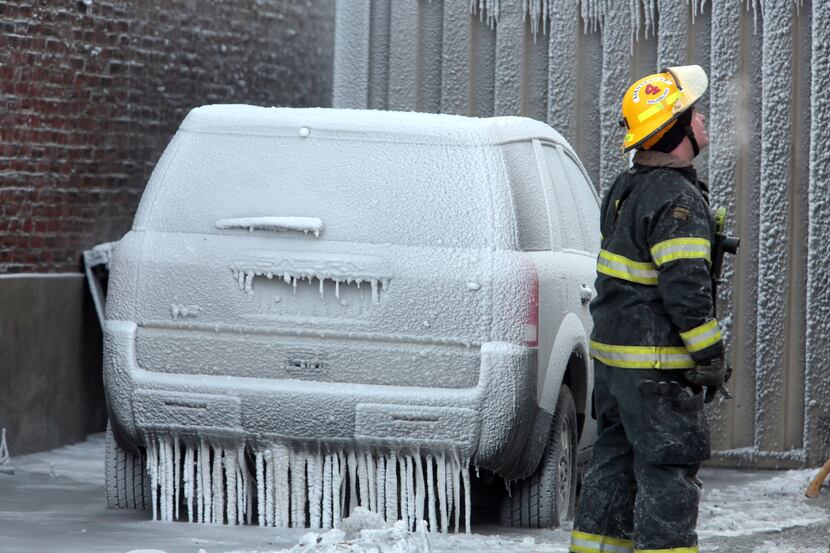 A Philadelphia firefighter stands near an ice-encased vehicle as he works the scene of an...