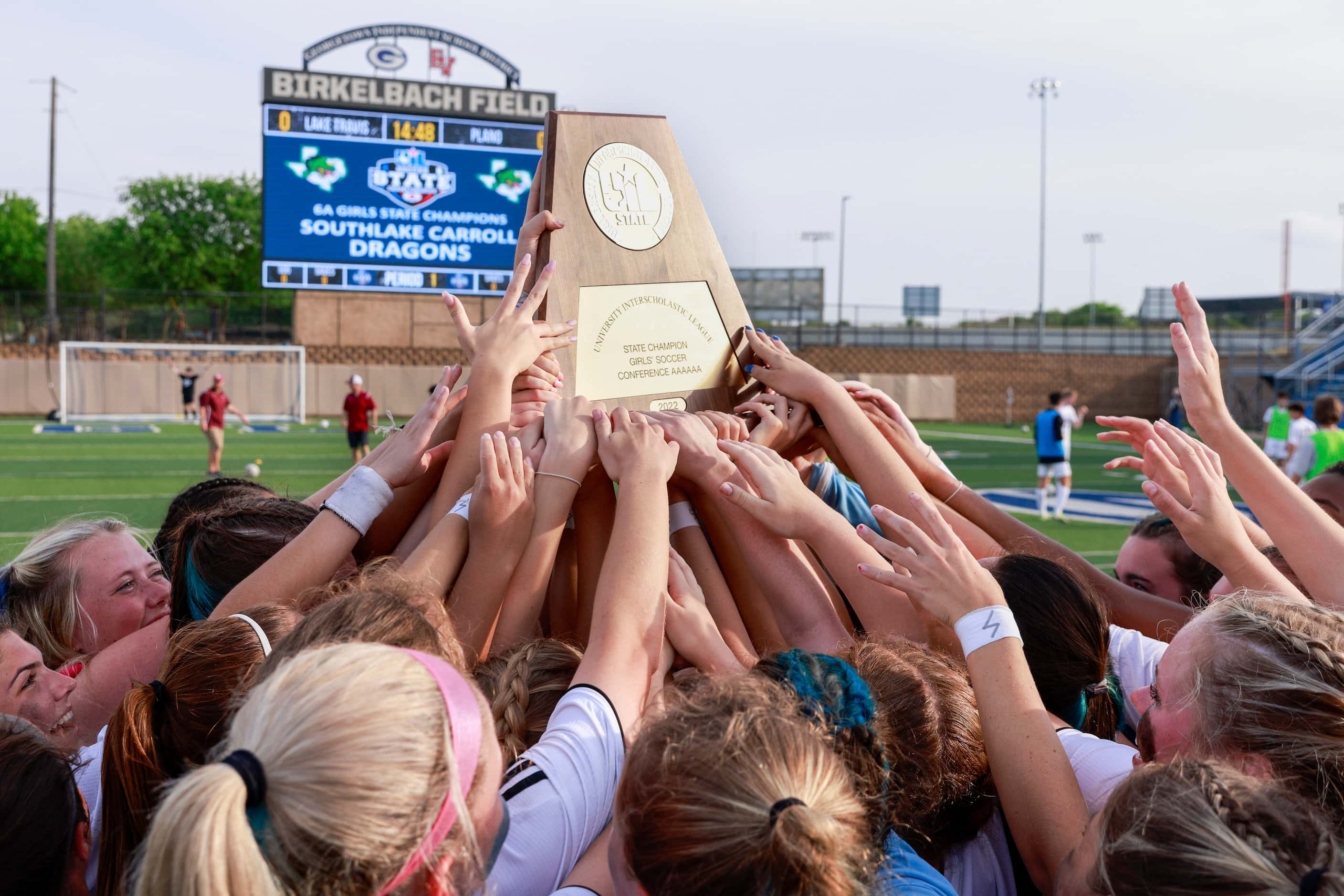 The Southlake Carroll team raises the Class 6A girls soccer state championship trophy at...