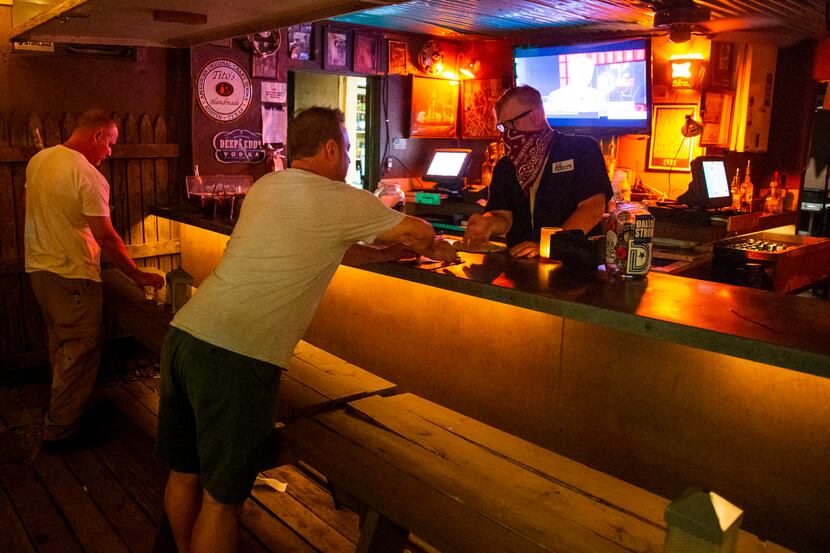 Customers settle up on their tabs with employee Zachary Anderson at the Lee Harvey's bar.