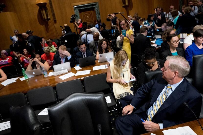 Sen. Lindsey Graham, R-S.C. waited as protesters disrupting a Senate Finance Committee...