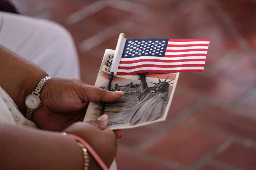 Una mujer sostiene una bandera estadounidense durante una ceremonia de naturalización...