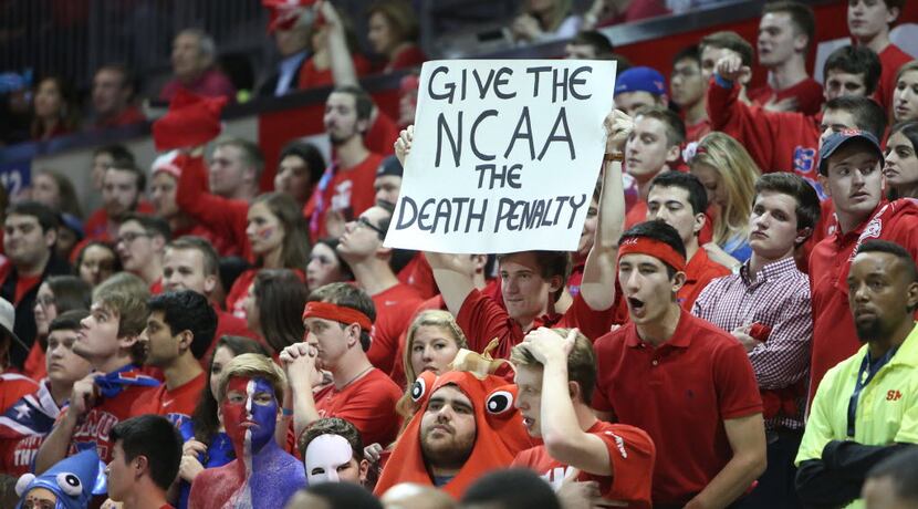 A fan holds up a sign referencing SMU football's 1987 punishment, an a current suspension of...