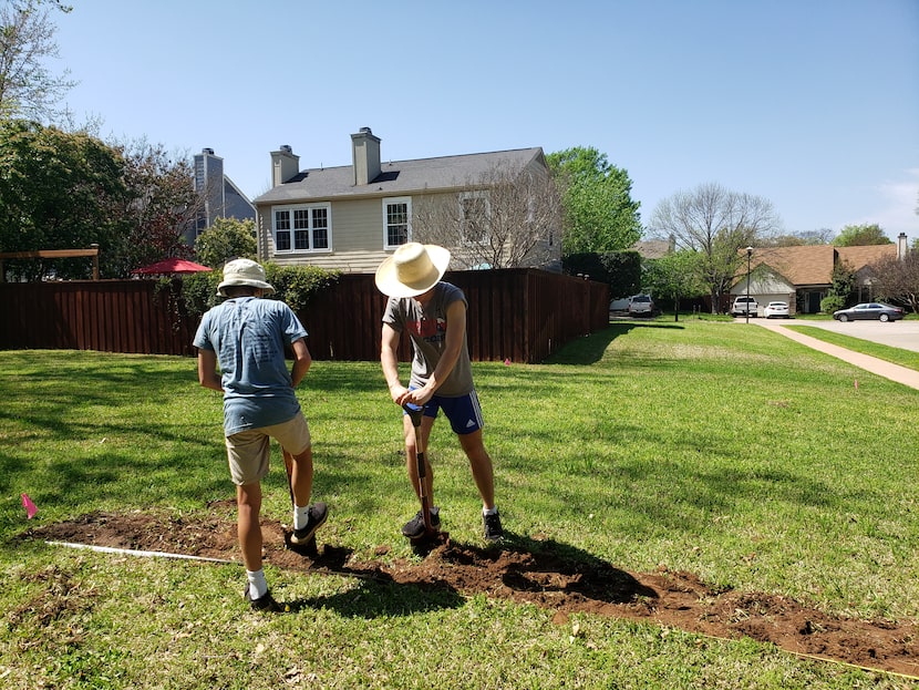 Mason (left) and Deric Marsh work on preparing their yard for a vegetable garden that would...