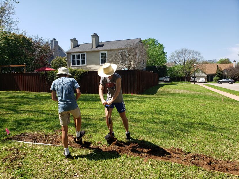Mason (left) and Deric Marsh work on preparing their yard for a vegetable garden that would...