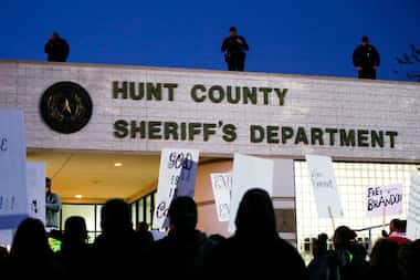 Roof top police watch as demonstrators gather at the Hunt County Sheriff's Department in...