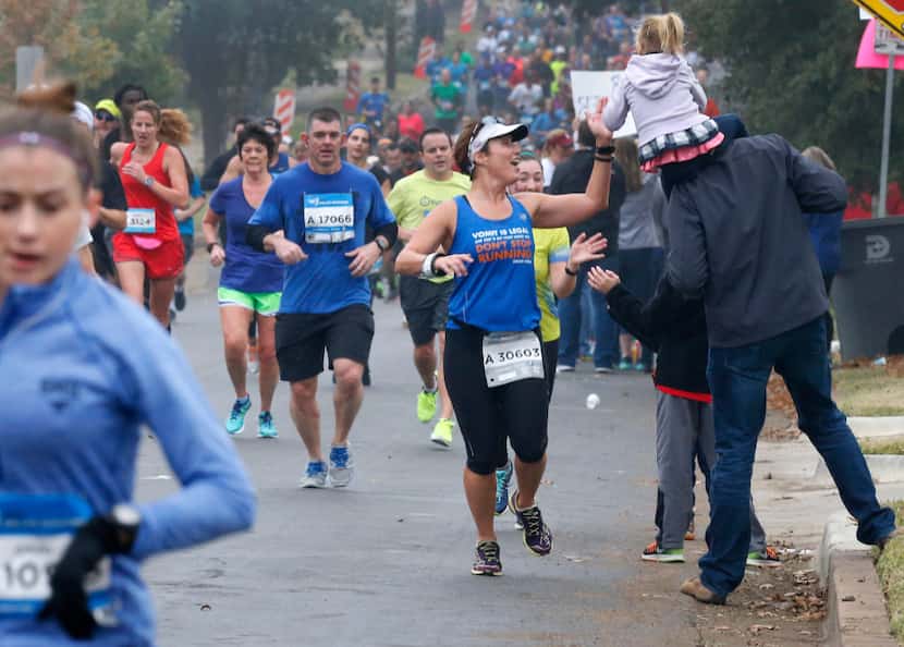 A runner high-fives a member of the crowd at the 8-mile mark of the 2016 BMW Dallas Marathon.