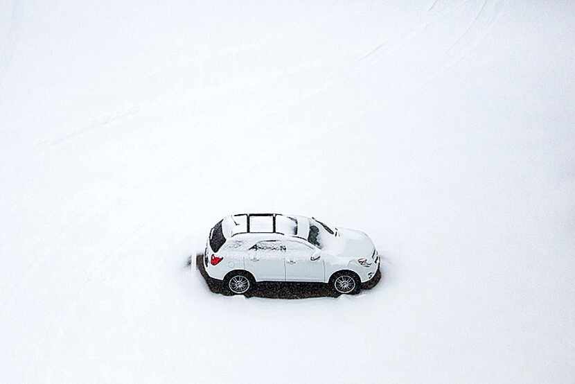  A single vehicle sits in a snow-covered parking lot in northeast Dallas as snow returns to...
