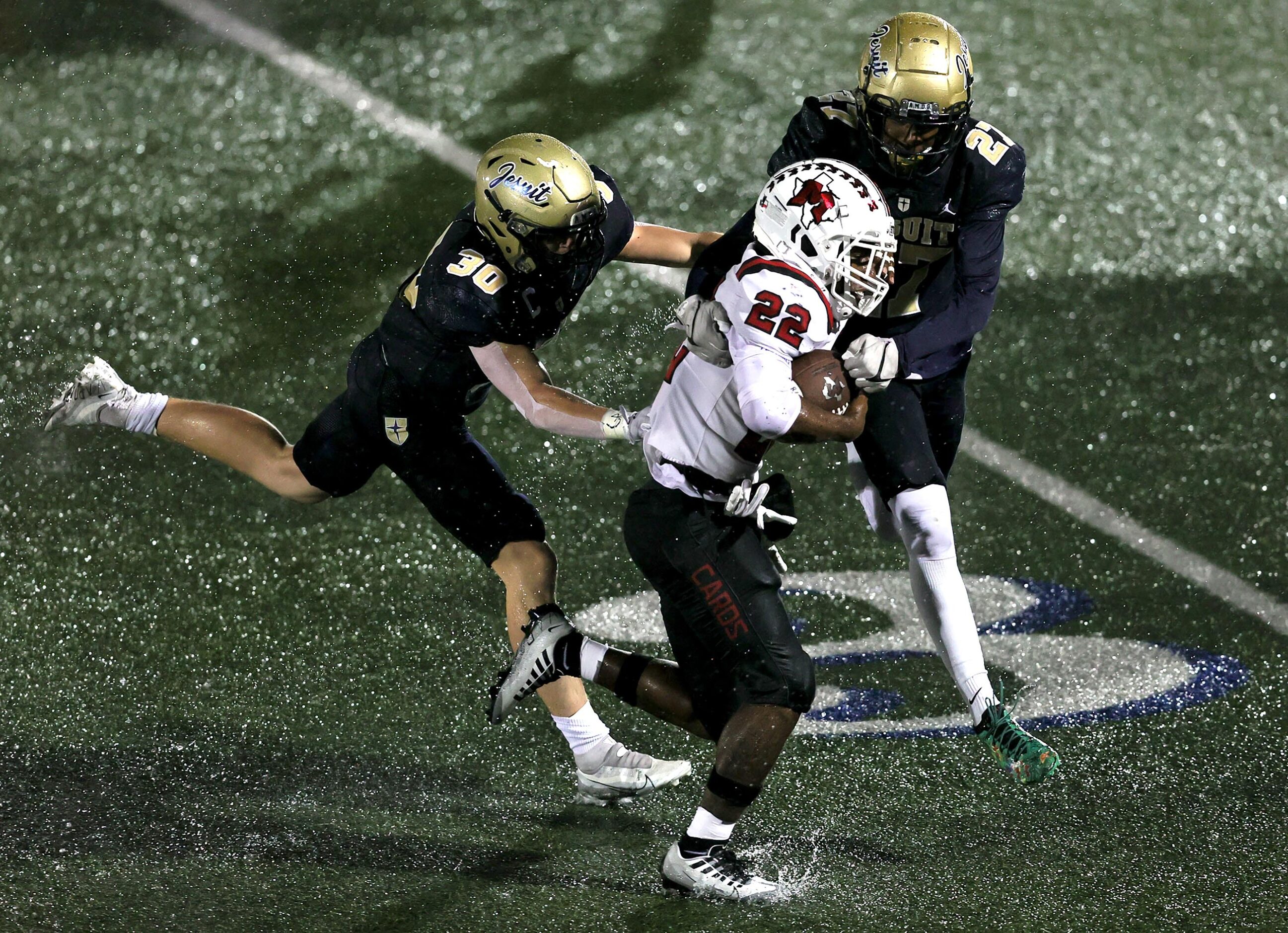 MacArthur running back Jerbrandin Henderson (22) tries to break free from Jesuit linebacker...