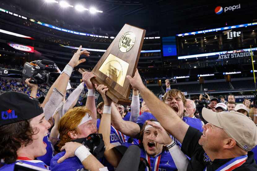 Gunter head coach Jake Fieszel passes the trophy to his players as they celebrate winning...