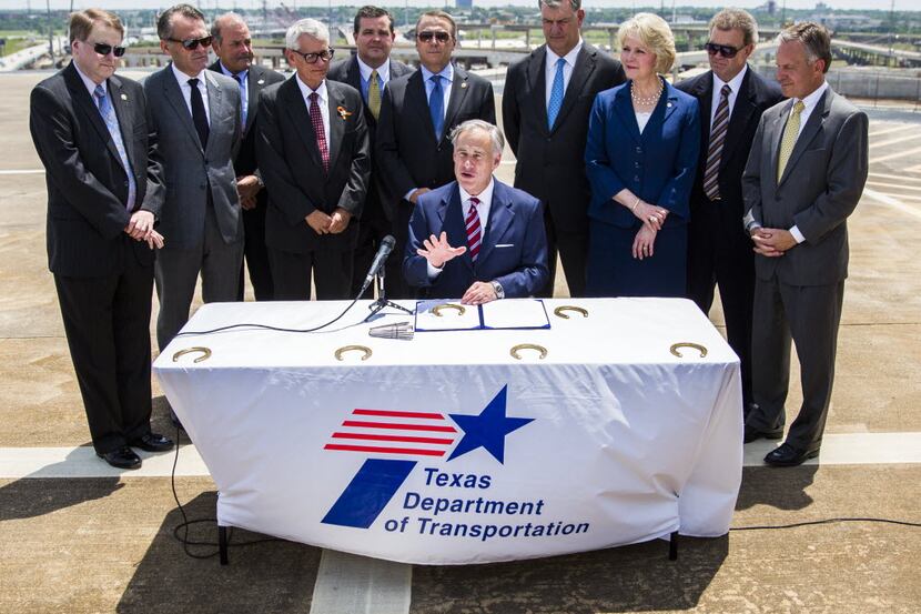  Governor Greg Abbott signs a transportation funding bill surrounded by legislators, Dallas...