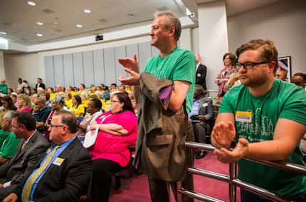 Lawrence Sweeny, center, and Ryan Roskey, right, applaud during public comment before the...