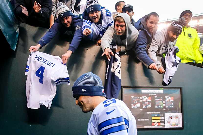 Fans yell to Dallas Cowboys quarterback Tony Romo as he walks off the field after a loss to...
