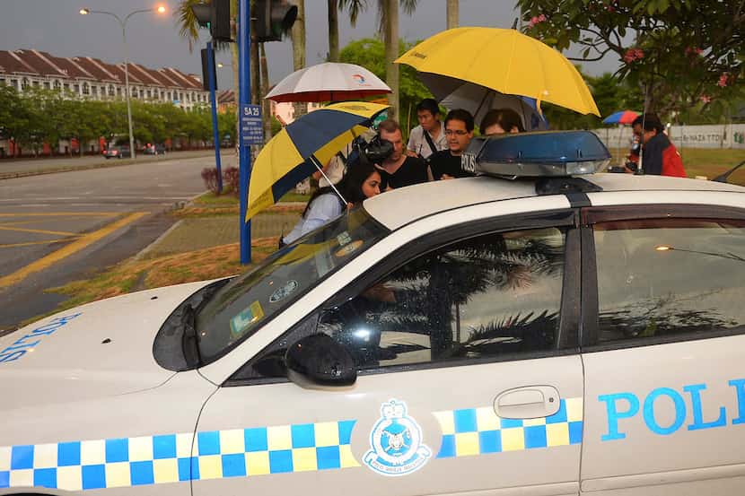 Journalists attempt to get information from Malaysian police officers after they came out of...